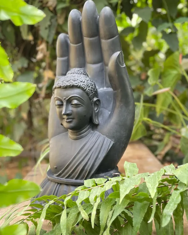 This 'Wisher of good things' is a beautifully crafted black marble statue of an ashirwad hastha (blessing hand) with a Buddha bust, ideal for a garden or indoor zen space.