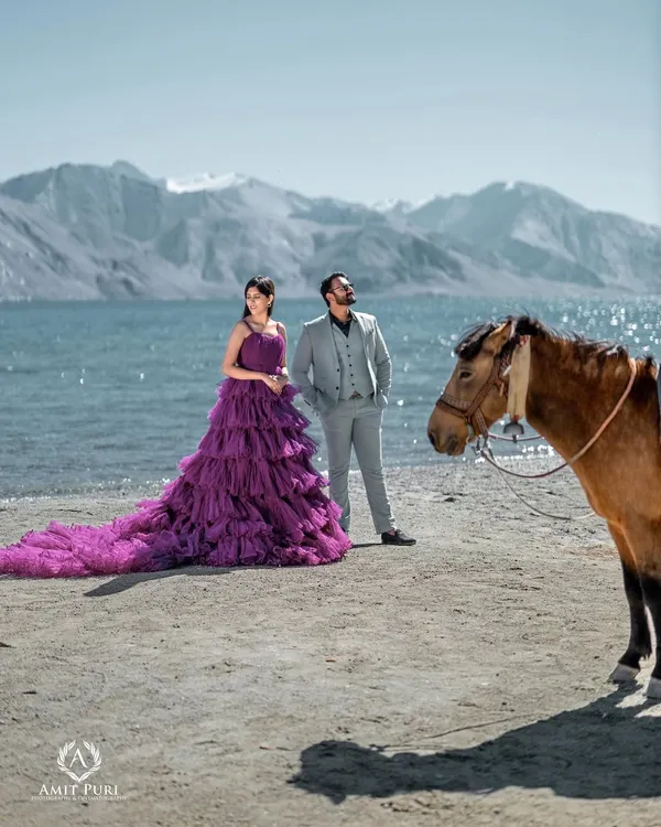A breathtaking portrait at Pangong Lake in Leh. The bride's magnificent purple gown stands out against the serene water and stark mountains, creating a scene of unparalleled scale and beauty.