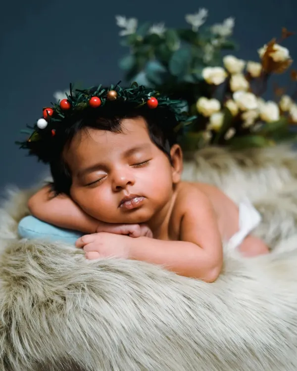 A peaceful sleeping newborn, captured during a Christmas-themed session. I use soft fur blankets and delicate props like this festive wreath to create a cozy and adorable setting for your baby's first photoshoot.