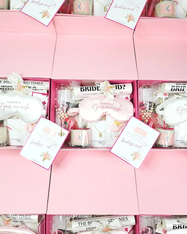 A bird's-eye view of a bulk order of my signature pink bridesmaid proposal boxes. Each one is filled with curated goodies like eye masks, scented candles, and personalized notes to make every member of your bride tribe feel special.