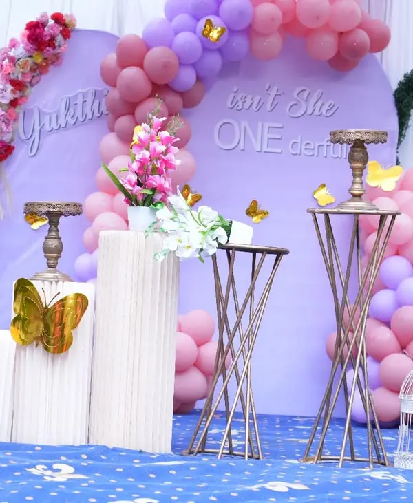 An elegant "Isn't She ONEderful" first birthday theme. This setup uses a soft lavender backdrop, pink and purple balloon arrangements, and decorative butterfly accents for a delicate and beautiful celebration.
