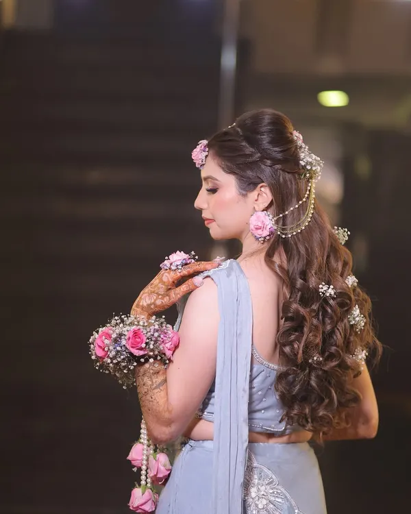 A side profile showing the elegant hairstyle with floral details that perfectly matches the mehndi theme.