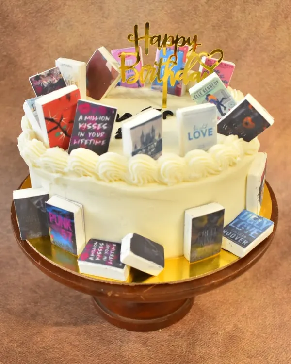 A book lover's dream cake. This cake is decorated with numerous miniature, edible book covers from popular authors and series, making it a perfect "Chapter 20" birthday celebration for a reader.