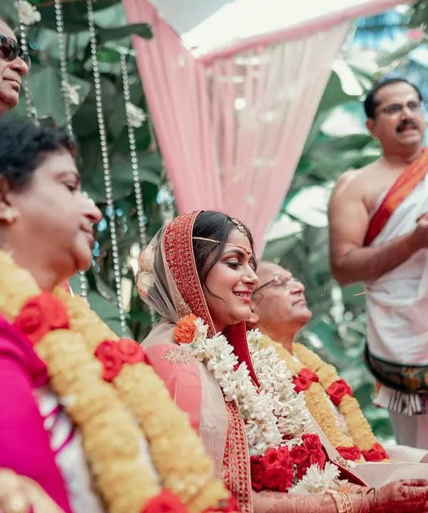A candid shot of a bride smiling during her wedding ceremony, surrounded by her proud parents. We focus on capturing the heartfelt emotions of not just the couple, but their families as well.