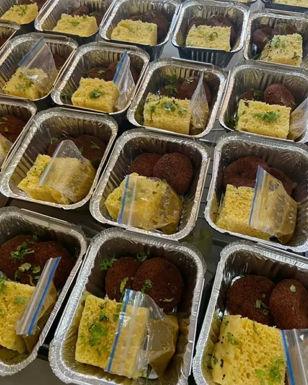 A look at a large order of 500 snack boxes being prepared for an NGO event. Each foil container is packed with fresh dhokla and veg cutlets, showing our capability to handle high-volume orders efficiently.