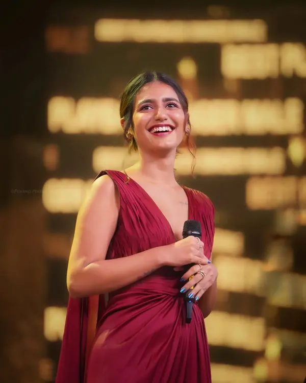 A candid shot of actress Priya P. Varrier smiling brightly while on stage at an awards show. Capturing genuine moments like this is my specialty, even in high-pressure event environments.