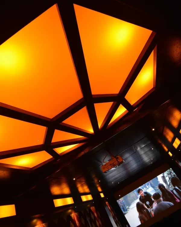 A close-up of a custom geometric ceiling light fixture with warm, diffused light. This type of architectural lighting adds a unique and sophisticated design element to any home theater.