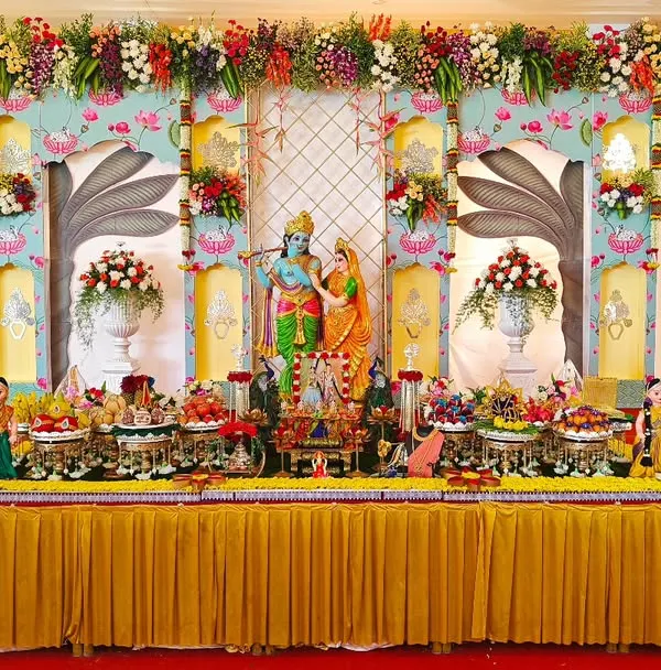 A specialized traditional plate decoration for an engagement, featuring a stunning backdrop with Radha and Krishna idols. The entire setup is a vibrant celebration of love and devotion.