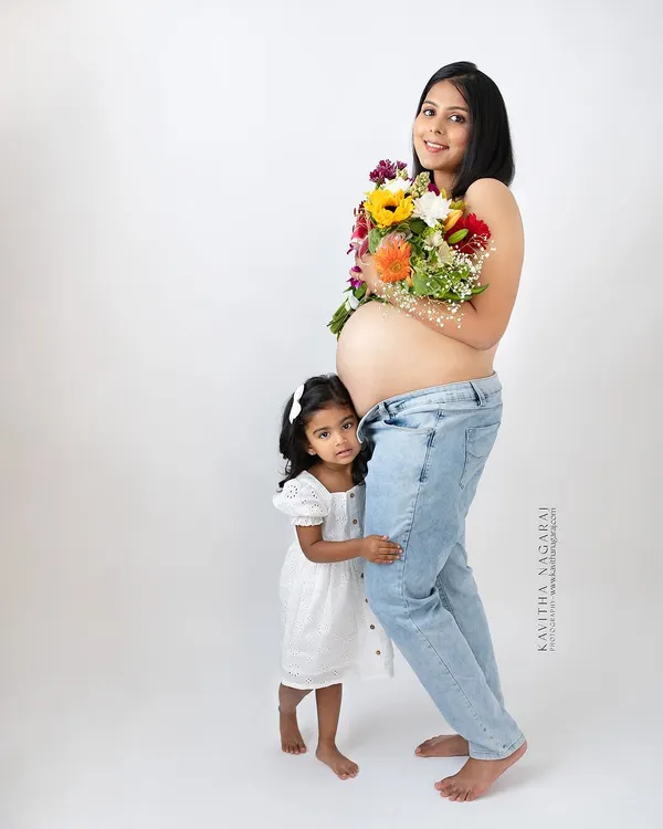 A mother-to-be and her daughter share a quiet moment of anticipation. Including older siblings in maternity shoots makes the memory even more special for the whole family.