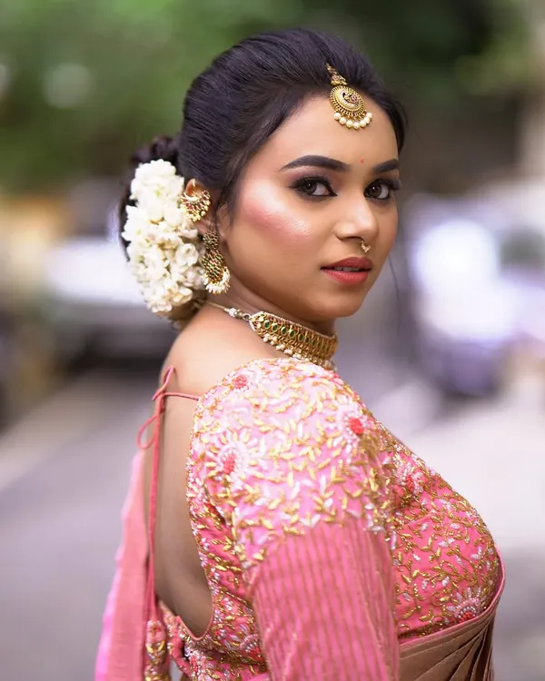 A side view of a classic bridal bun, showing how the fresh jasmine flowers are neatly arranged. This hairstyle is perfect for showcasing an ornate blouse and heavy jewelry.