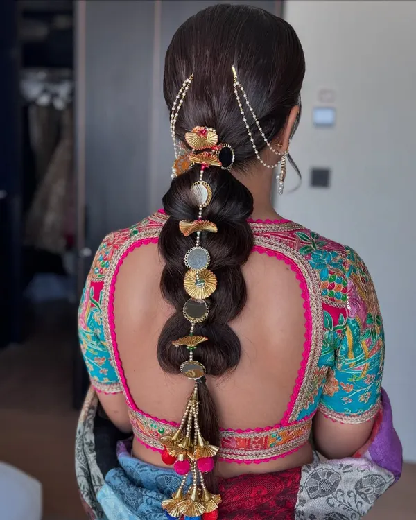 A beautiful example of an embellished bubble braid. This traditional hairstyle is elevated with intricate gold and pearl accessories, making it perfect for a bride.