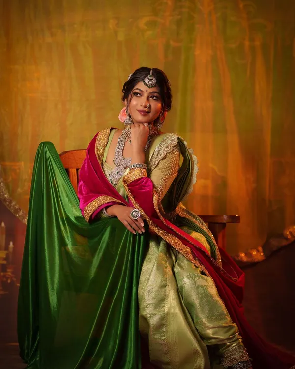 A full-length portrait of the 'Peshwe Bai' or Maratha queen look. Seated with poise, this image showcases the complete royal attire, including the unique draping style and rich fabrics.