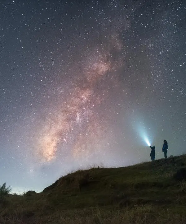 Two participants stand in awe under the Milky Way in Singalila National Park. This frame, a blend of two images, shows the sheer scale of our galaxy compared to us.