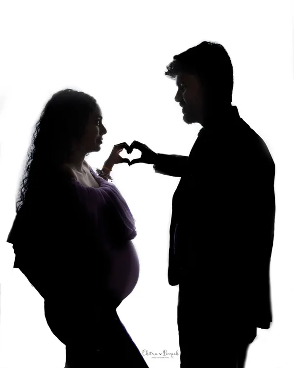 A beautiful silhouette of a couple creating a heart with their hands. This artistic shot is a simple yet powerful symbol of their love.