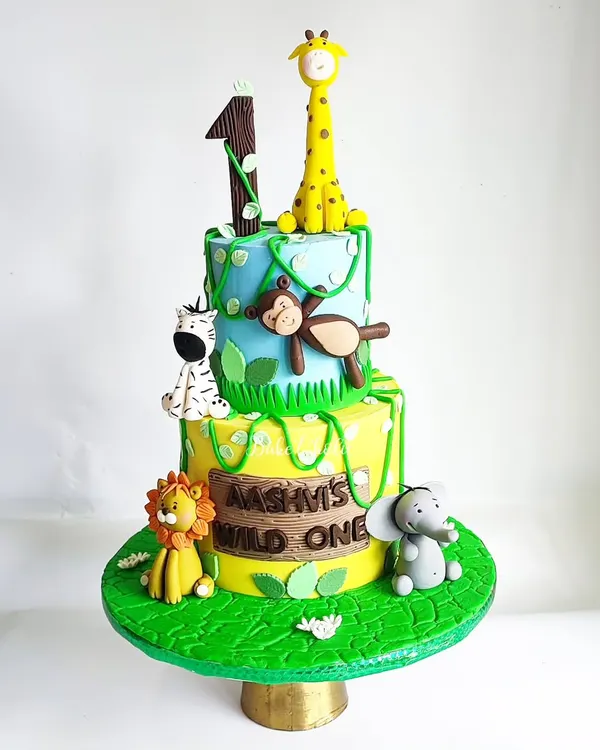 A wild and wonderful jungle theme for Aashvi's first birthday! This 3kg eggless chocolate truffle cake is two tiers of fun, with handcrafted fondant animals like a giraffe, monkey, zebra, lion, and elephant.