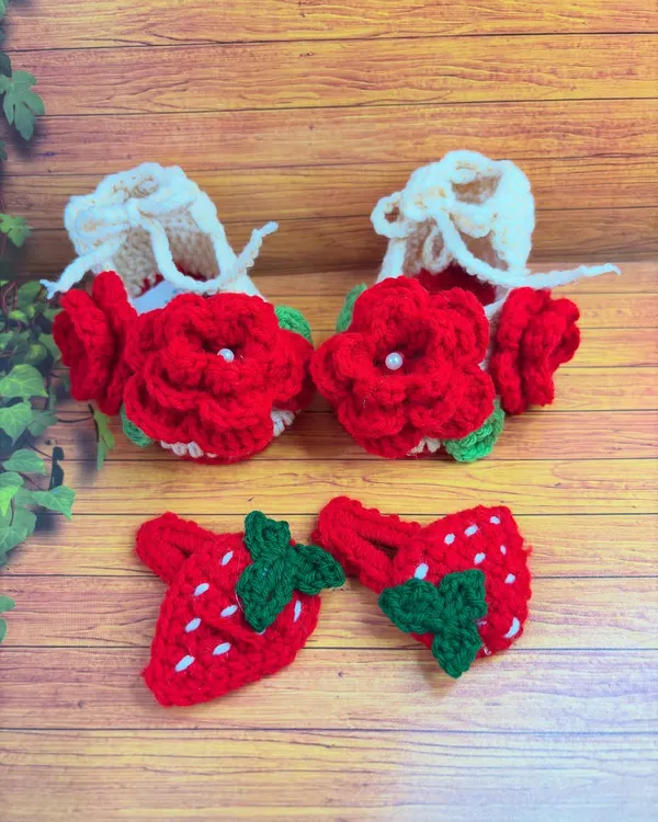 This sweet set includes off-white booties with red floral details and a pair of matching strawberry-shaped hair clips.