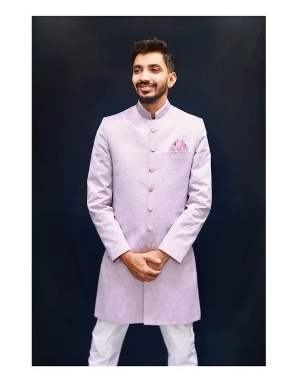 This lavender Indo-western is a real stunner and a customer favorite. It's made from a beautiful textured fabric with a modern geometric pattern and paired with clean white trousers. This outfit is perfect for making a stylish statement at a sangeet, reception, or any special occasion.