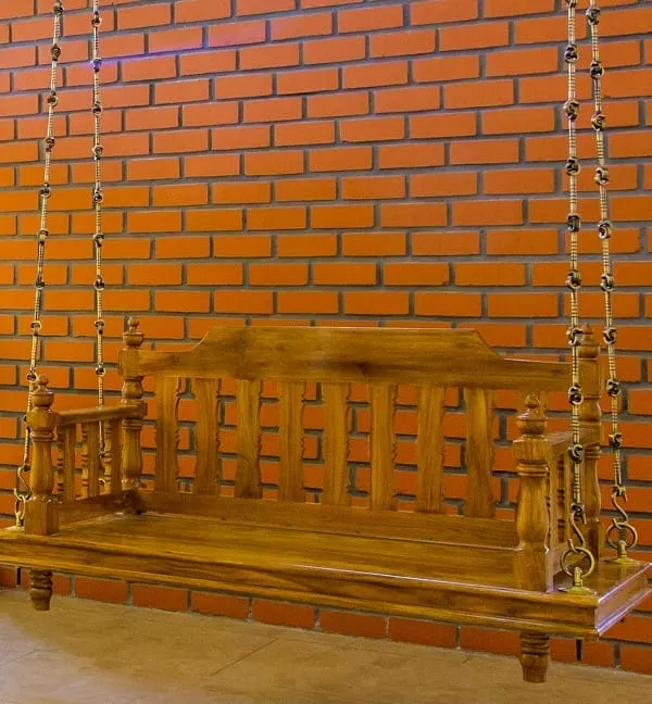The traditional wooden 'jula', or swing, is a centerpiece in this home, set against a warm exposed brick wall. It’s a nostalgic element that invites relaxation and conversation.