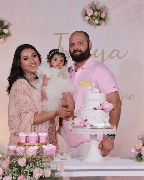 A beautiful family portrait at their daughter's first birthday. The soft pink and floral decor creates a gentle and loving atmosphere for the celebration.