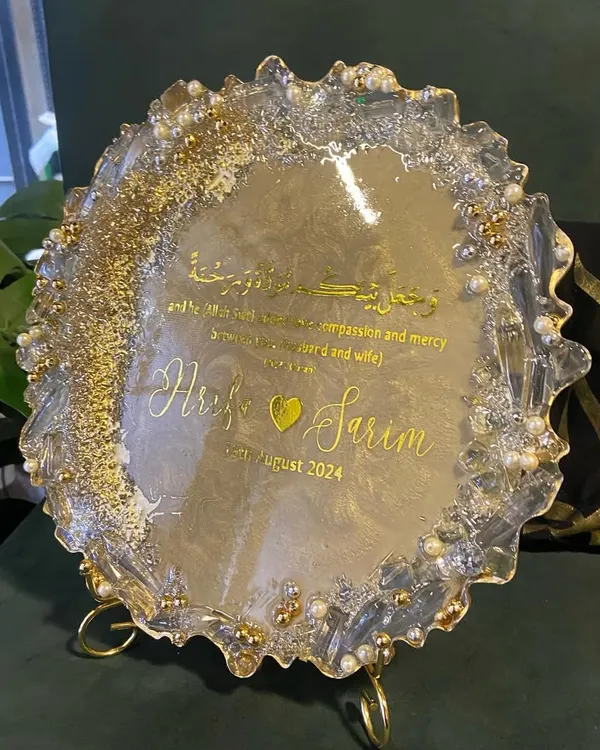 A beautiful resin engagement plaque designed to celebrate a new union. This piece features the couple's names, their special date, and a Quranic verse, all set in a shimmering gold and pearl design with a geode-style edge.