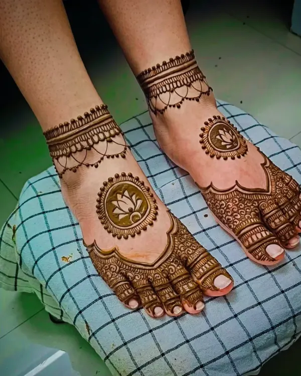 A simple and elegant foot mehandi design featuring a lotus mandala on the center of the foot and a delicate chain-like pattern around the ankle.
