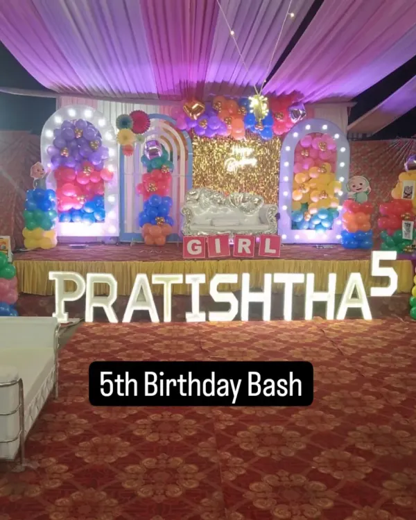 A vibrant and colorful stage for Pratishtha's 5th birthday bash. The double-arched backdrop with balloon columns and large light-up letters fills the space beautifully.
