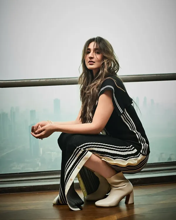 An editorial shoot with Dhvani Bhanushali against the Mumbai skyline. She wears a chic black and white striped co-ord set from Lovebirds Studio, creating a modern and graphic look.