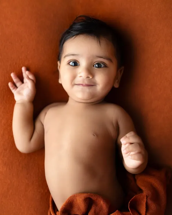Six months old and full of personality. This little one's curious eyes and sweet smirk are a perfect example of the adorable expressions we capture during sitter sessions.