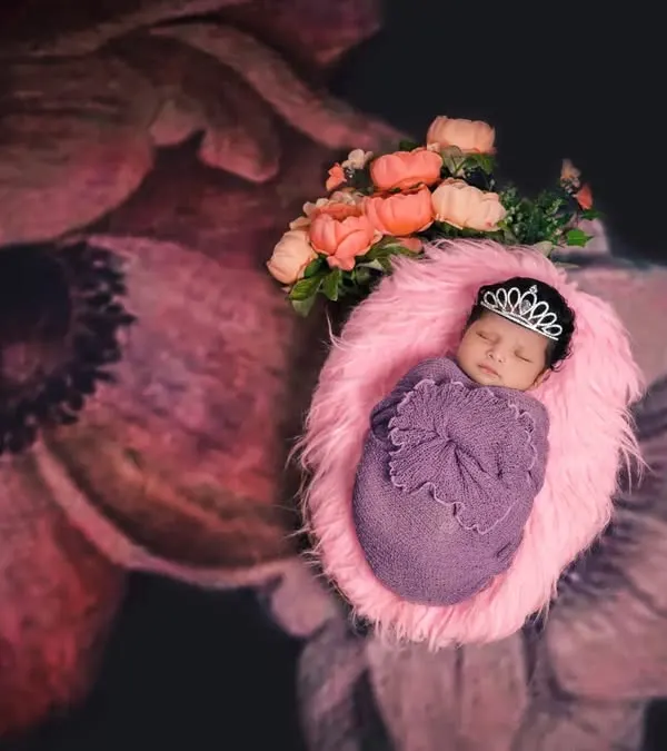 A little princess is born. This newborn is wrapped in a beautiful floral theme, complete with a tiny tiara, showcasing our creative approach to newborn photography.