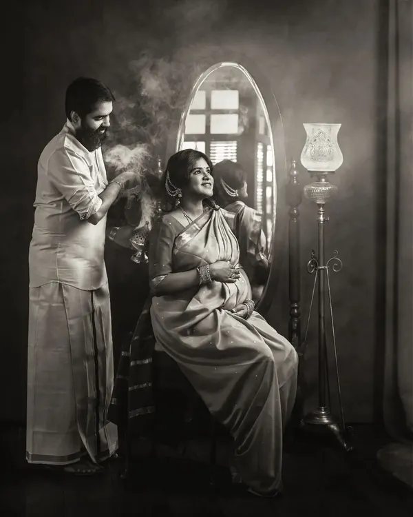 A dramatic black and white studio portrait of a couple. The monochrome treatment enhances the vintage feel, the texture of the smoke, and the emotional intensity of their connection.