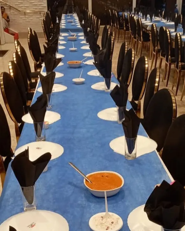 A long view of our formal dining setup. The striking blue and black theme, with neatly folded napkins and pre-set dishes, shows our ability to execute a sophisticated and large-scale seated dinner service.