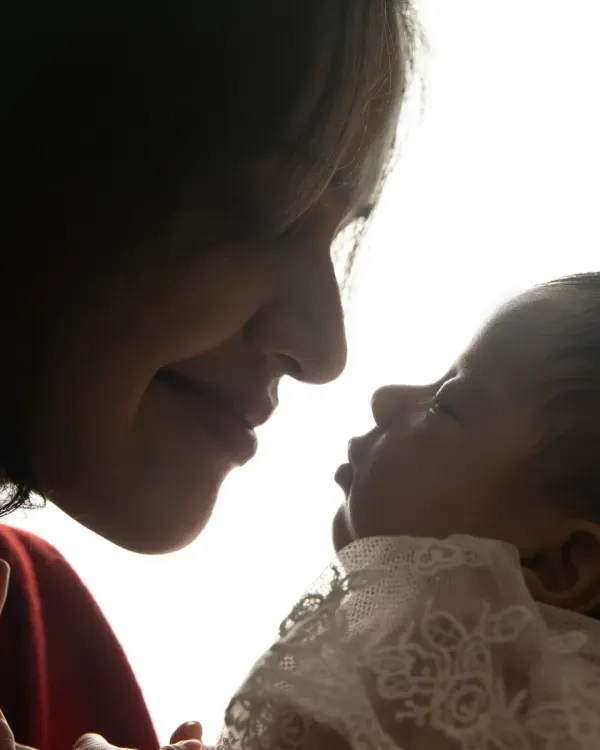 A powerful silhouette shot capturing the tender profile of a mother as she looks down at her newborn baby, highlighting their instant, profound connection.