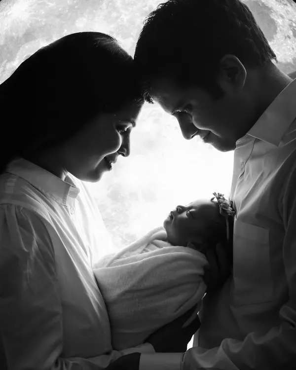 A timeless black and white portrait capturing the profound love between new parents and their baby. This artistic silhouette style, created in our studio, focuses on the emotional connection that welcomes a new life into the family.