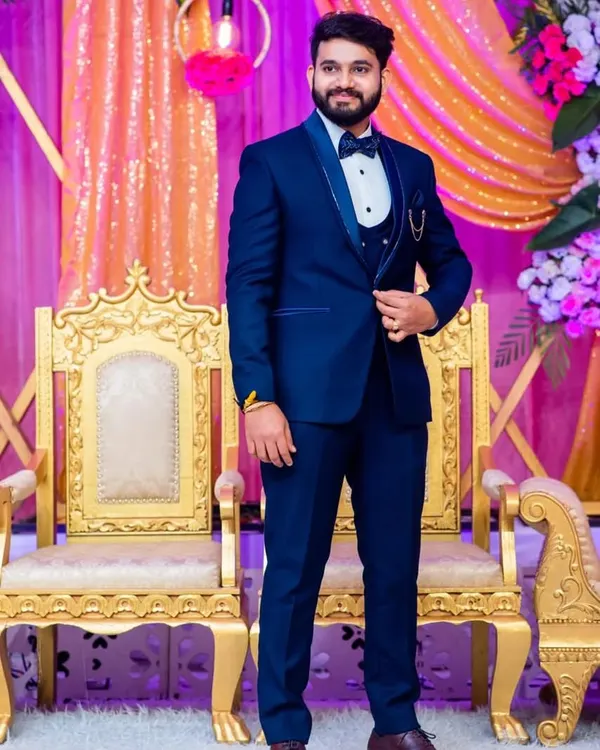A classic blue tuxedo is always a great choice for a wedding reception. This three-piece set is complete with a satin shawl lapel and a bow tie for a timeless groom's outfit.