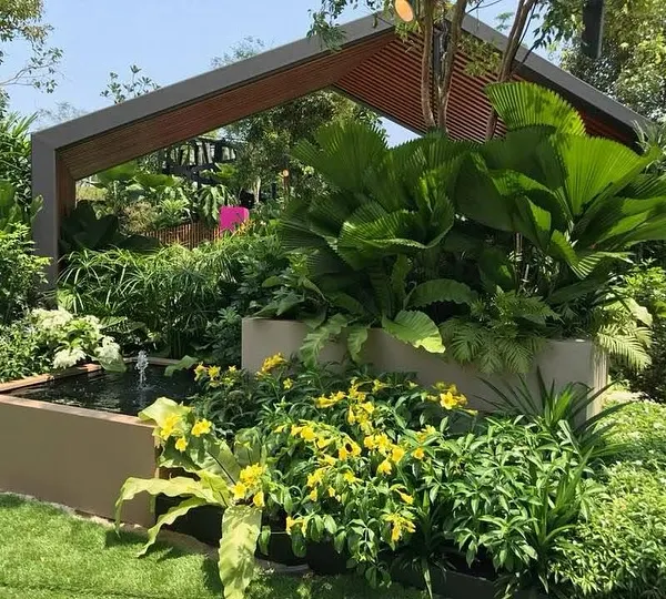 A glimpse into a modern tropical paradise I designed. This space features a custom-built gazebo for relaxation, surrounded by lush, layered greenery and a serene water feature, creating a perfect private retreat.