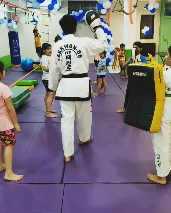 A Taekwondo player doesn't need a weapon, they are one. Here, an instructor guides a student through punching drills, focusing on technique and power in our safe, padded training area.