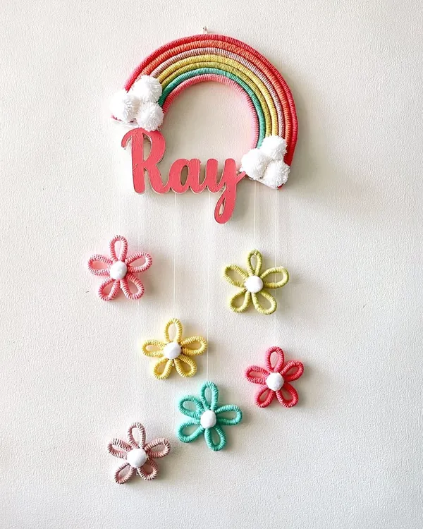This custom rainbow nameplate, made for a special little one named Ray, is one of my favorite creations. I love combining vibrant colors with soft pom-pom clouds and delicate hanging flowers to create something truly magical for a child's room. Each nameplate is handcrafted to bring your unique ideas to life.