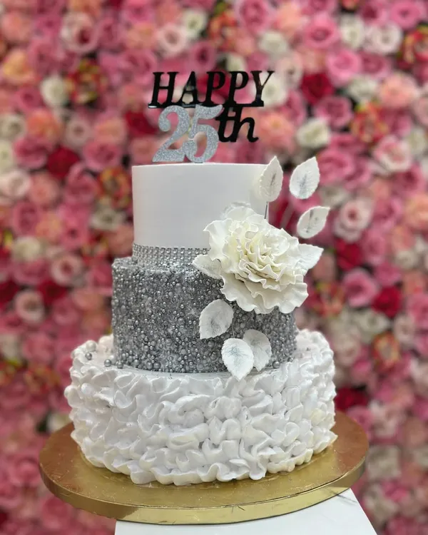 This elegant, three-tiered cake was the centerpiece for a 25th anniversary. It features a sparkling silver sequin tier, delicate ruffles, and a beautiful handcrafted sugar flower, showing my skill in creating sophisticated designs for milestone celebrations.