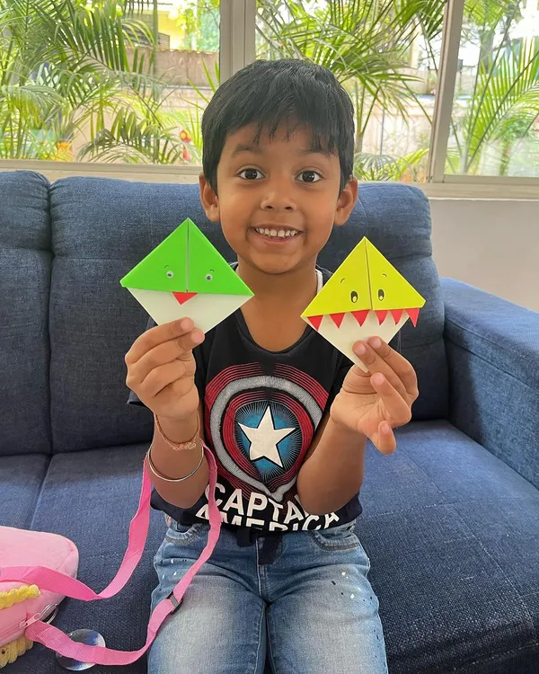 Look at that proud smile. We made these quirky frog and shark origami bookmarks, turning simple paper into fun reading buddies. It's all about finding joy in these little creations.