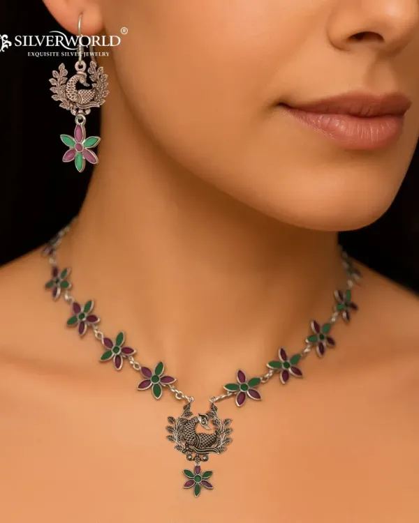 This is one of our signature oxidized silver necklace sets, featuring an intricate peacock motif and colorful floral details. It perfectly represents our skill in combining traditional Indian designs with a touch of modern artistry, making it a versatile piece for festive occasions.