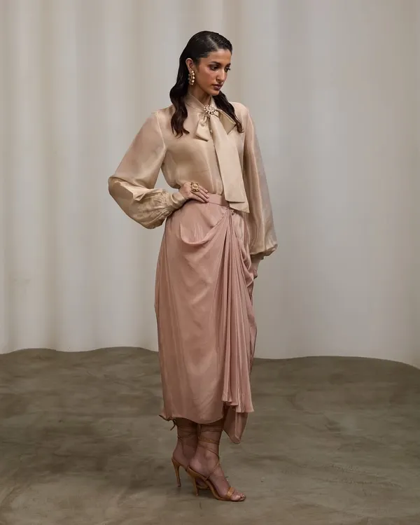 A full-length studio shot for a designer's pret couture line. The elegant pose and soft lighting highlight the graceful drape and flow of this indo-western outfit.
