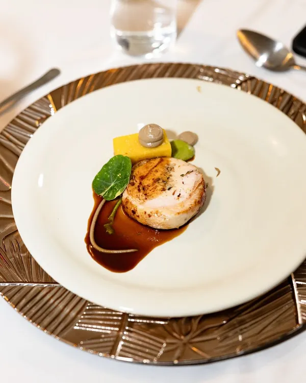 A signature dish, the Ballotine of Chicken. This heritage chicken is deboned, stuffed with a mushroom mousseline, and served with panisse and a port wine reduction.