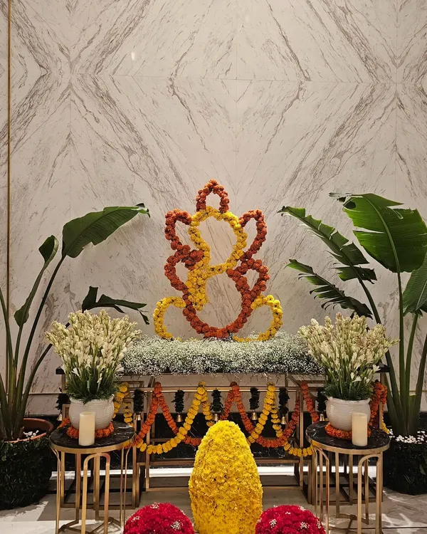 A modern and elegant Ganesh Chaturthi setup I designed for the Fairmont Mumbai hotel lobby. The centerpiece is a Ganesha silhouette crafted from fresh orange and yellow marigold flowers, set on a bed of baby's breath and flanked by white tuberoses and lush plants for a serene welcome.