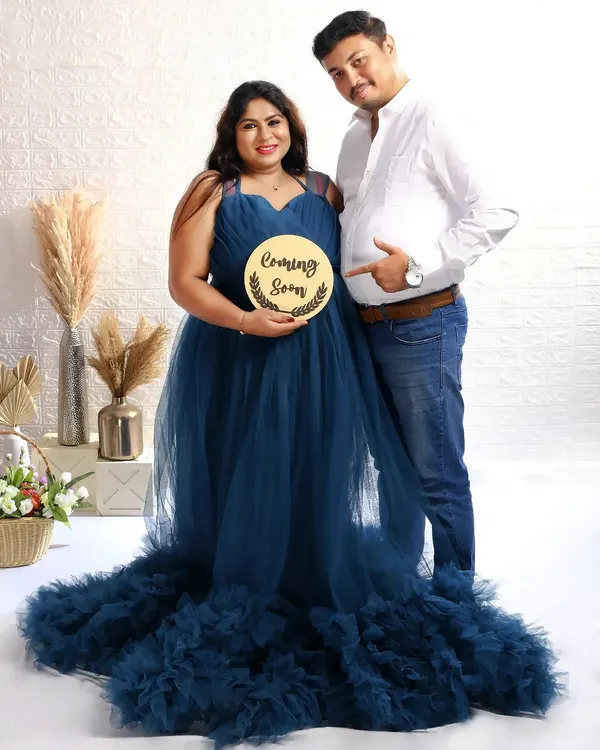 A classic announcement shot with a "Coming Soon" sign. The dad-to-be playfully points to the baby bump, sharing their happy news with the world.
