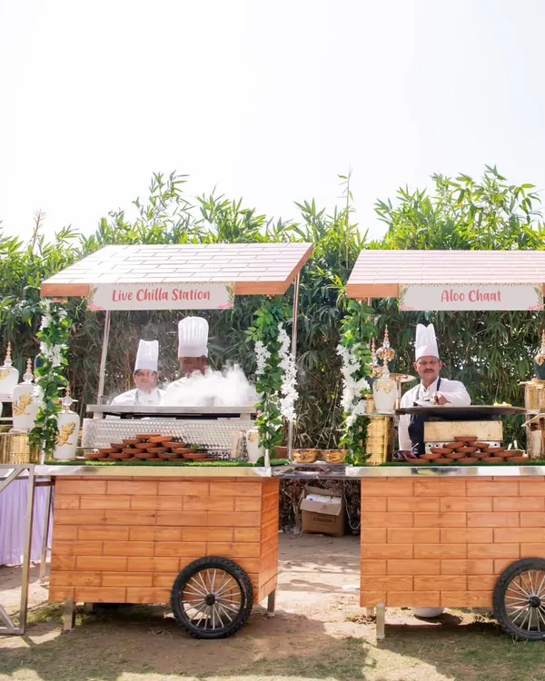 My charming wooden food carts, or 'thelas', set up for an outdoor event. Here you can see the Live Chilla Station and Aloo Chaat station, ready to serve fresh street food favorites.