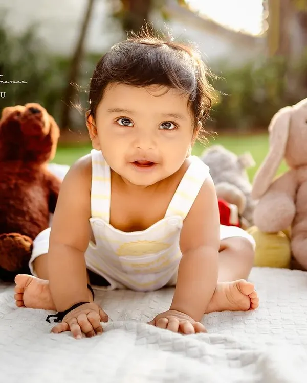 Sunshine and giggles. This outdoor sitter session captures a baby's curiosity as she explores the world around her, surrounded by her favorite stuffed animals.