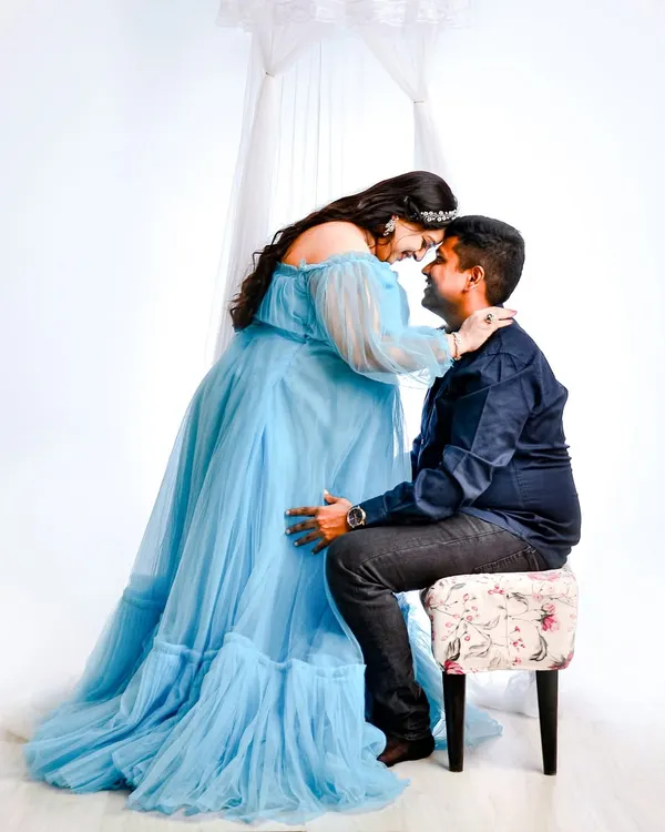 An intimate gaze between partners, framed by the soft fabric of our light blue maternity gown. These high-key shots create a bright, dreamy atmosphere.