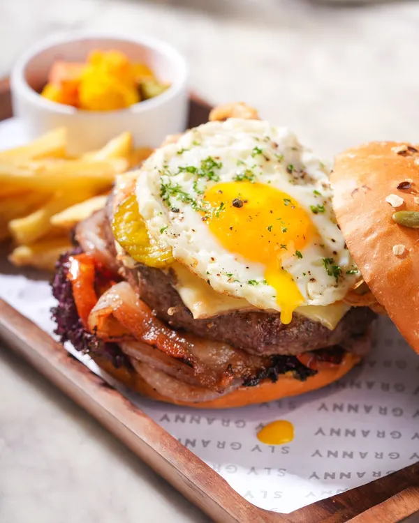 Take a bite of pure bliss. This is my signature burger, stacked high with a juicy patty, crispy bacon, cheese, and a perfectly fried egg.