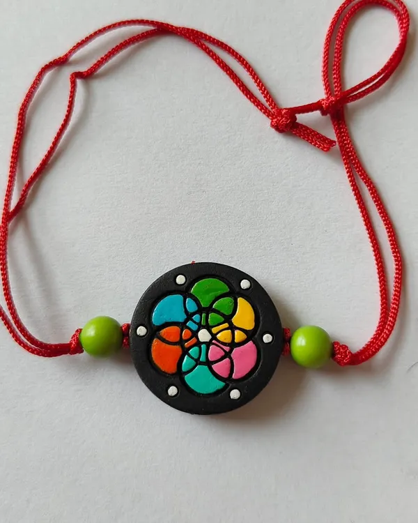 This eco-friendly terracotta rakhi features a colorful stained-glass pattern on a black base. It's a unique and artistic choice for celebrating Rakshabandhan.