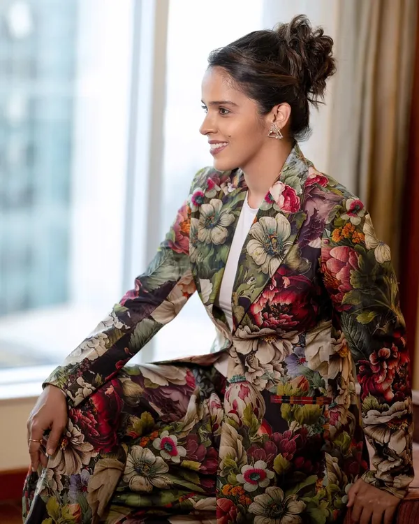 A candid portrait of Saina Nehwal, captured during a moment of relaxation. The natural light from the window gives the shot a soft, authentic feel, showcasing her personality beyond the badminton court.